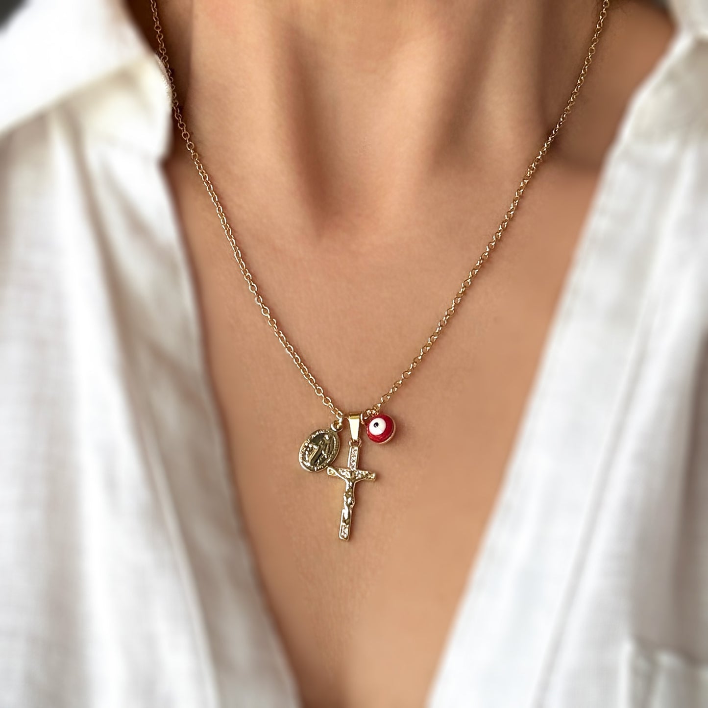 Necklace with three charms on a person wearing a white shirt