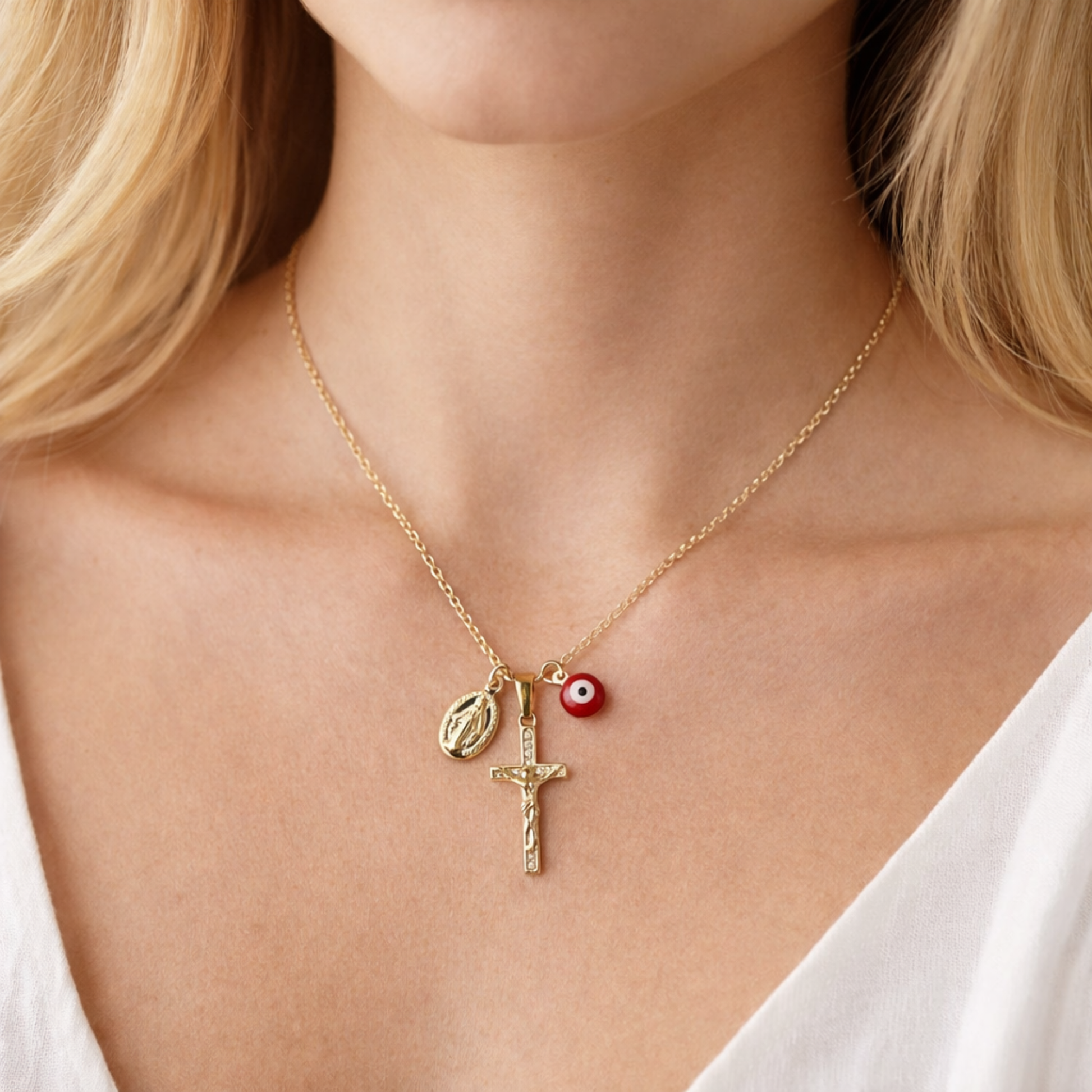 Gold necklace with three charms worn by a person
