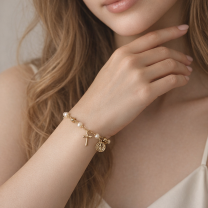 Close-up of a woman's hand wearing a gold bracelet with charms against a neutral background