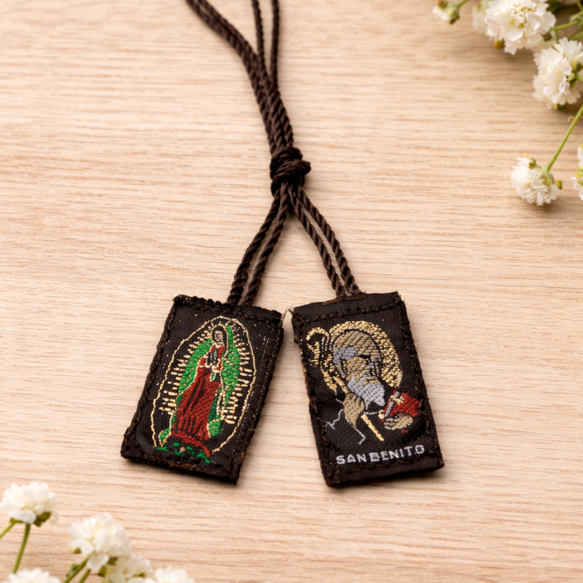 Two embroidered pendants on a string with floral decorations on a wooden surface
