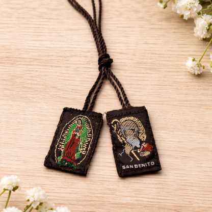 Two embroidered pendants on a string with floral decorations on a wooden surface