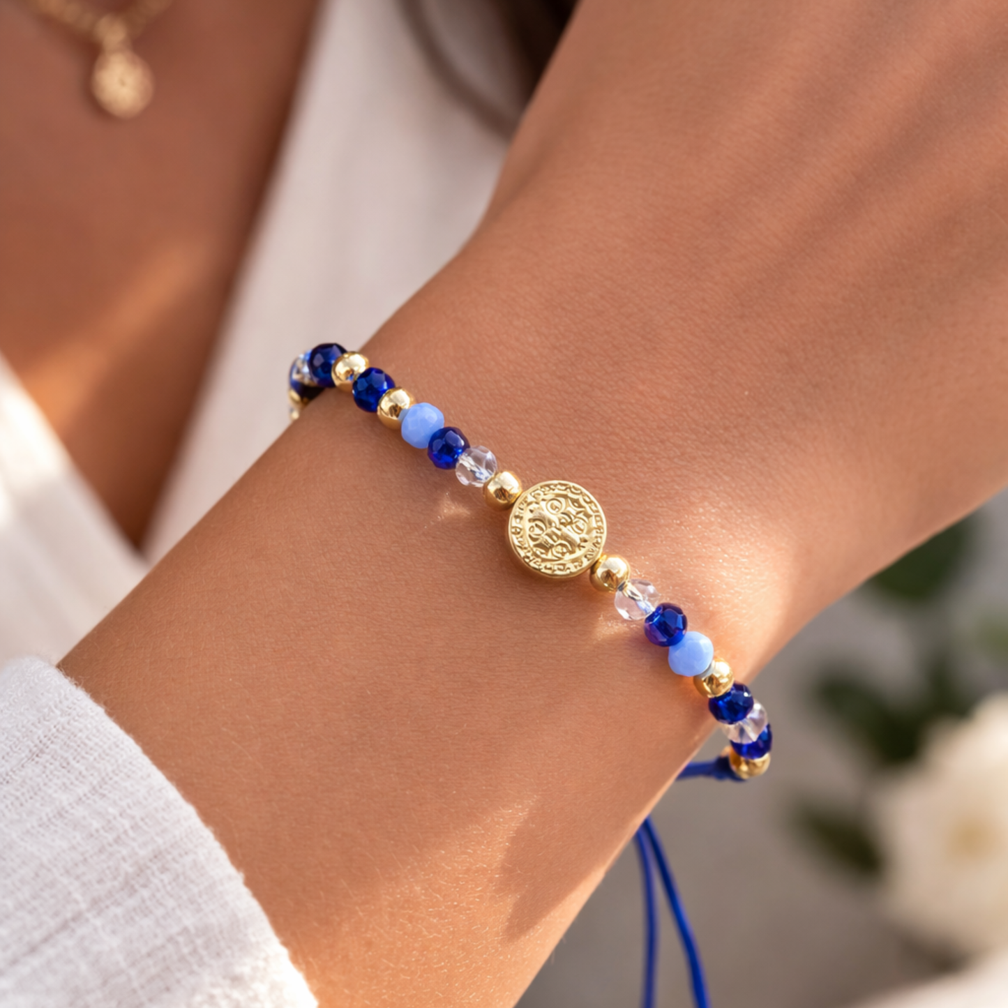 Bracelet with blue and gold beads on a wrist against a neutral background