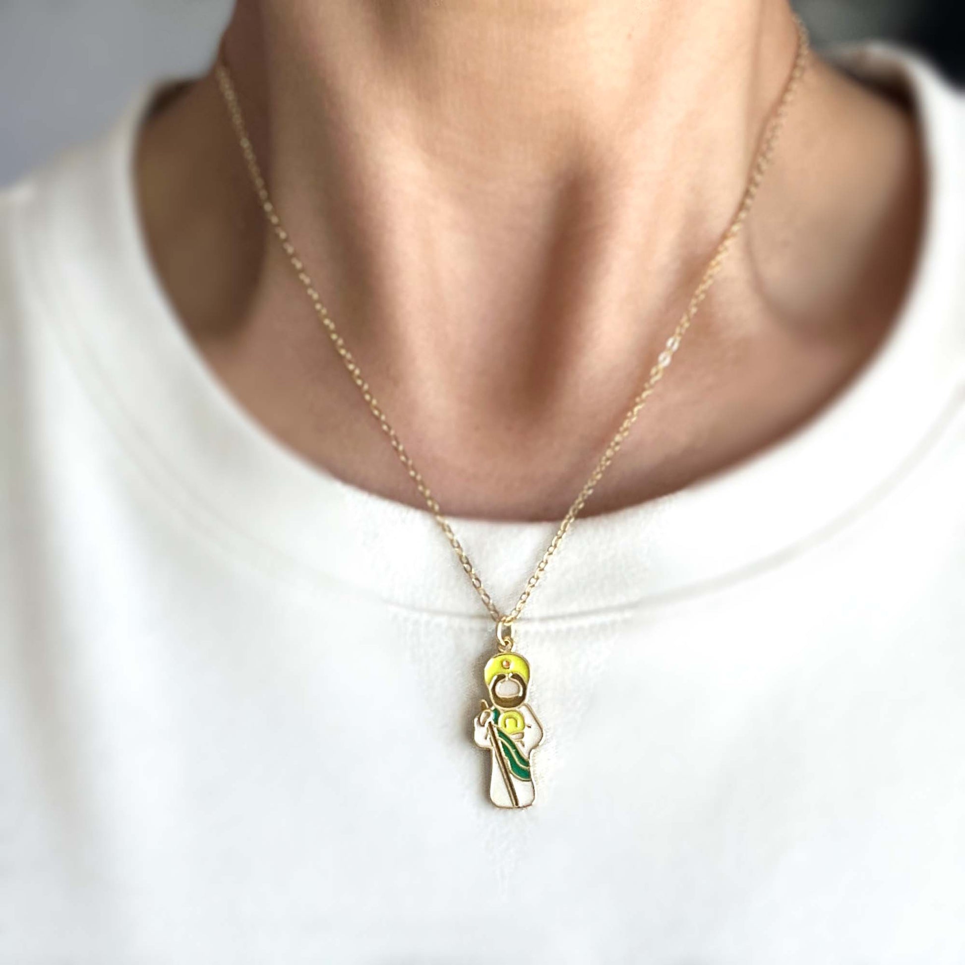 Gold necklace with a pendant of Saint Jude on a white shirt