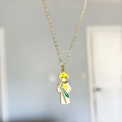 Gold necklace with a pendant of a Saint Jude a yellow flower on a neutral background