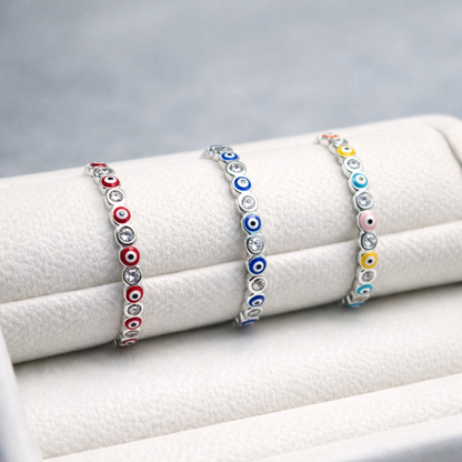 Three colorful evil eye rings on a white jewelry display.