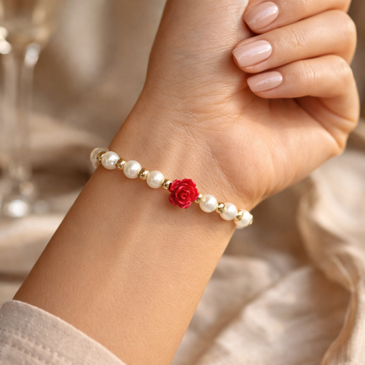 Pearl bracelet with a red flower charm on a wrist, blurred background
