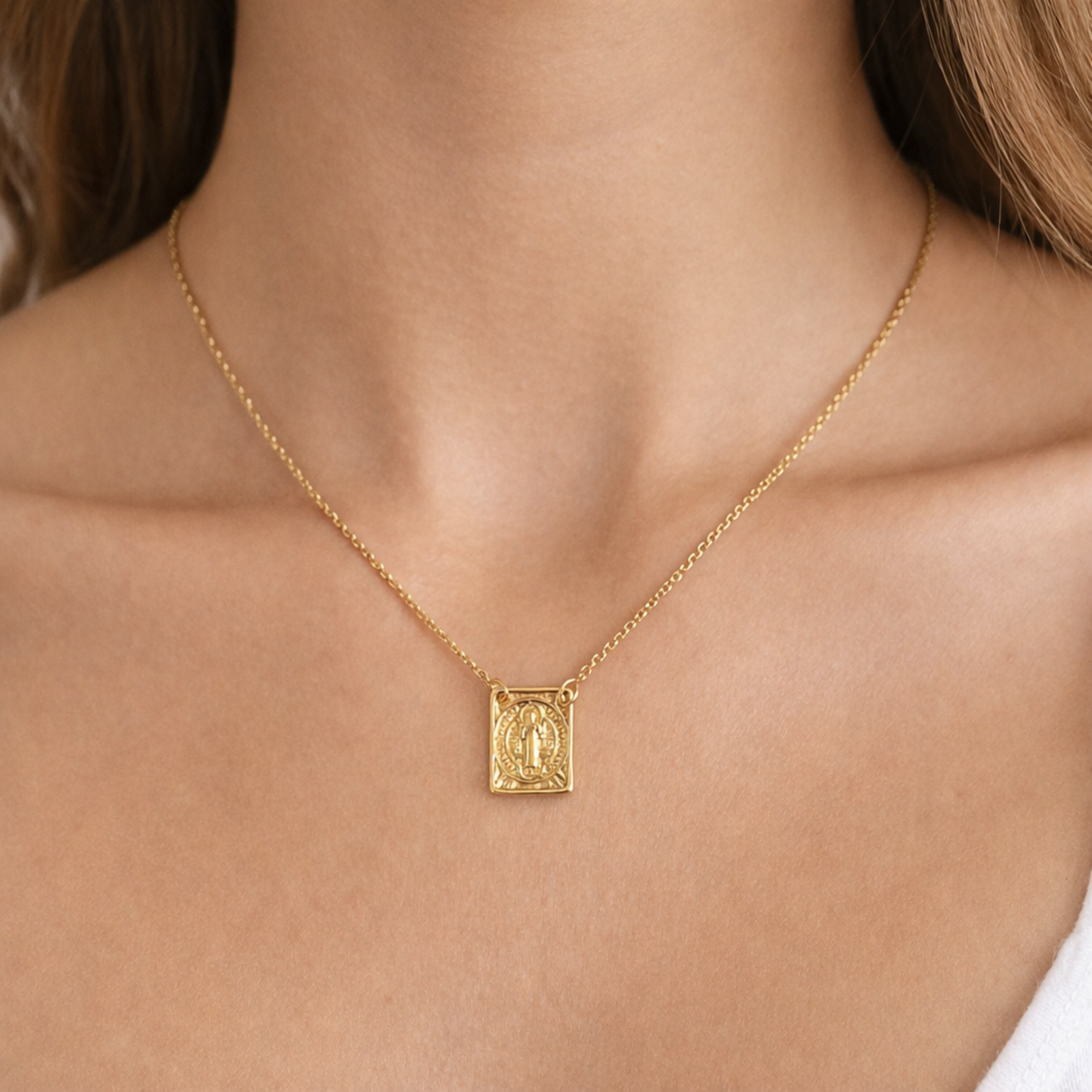 Gold necklace with a pendant of Saint Benedict on a person's neck